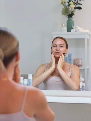Frau bei der Anwendung der Daily Glow Up Daily Routine vor dem Spiegel.