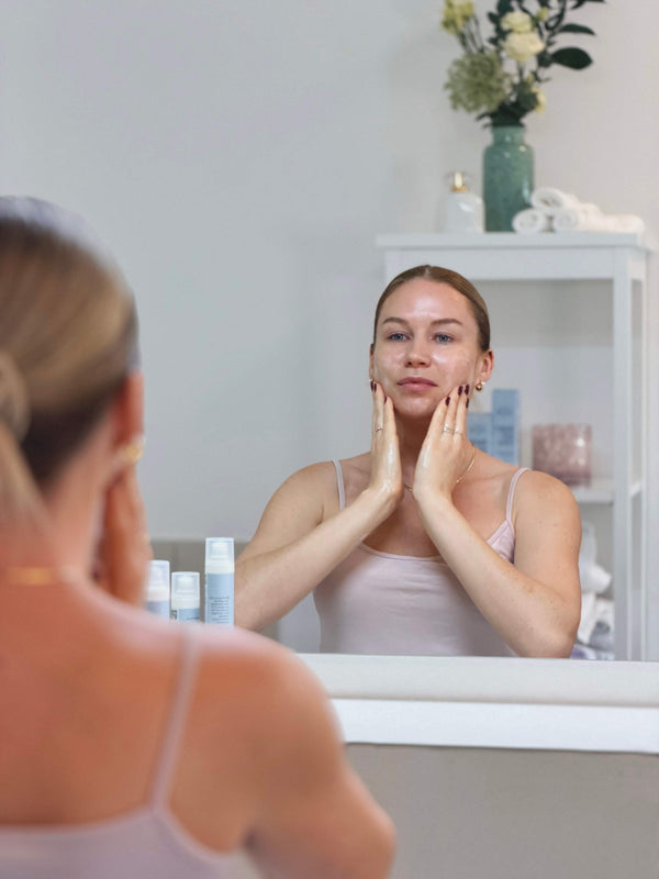 Frau bei der Anwendung der Daily Glow Up Daily Routine vor dem Spiegel.