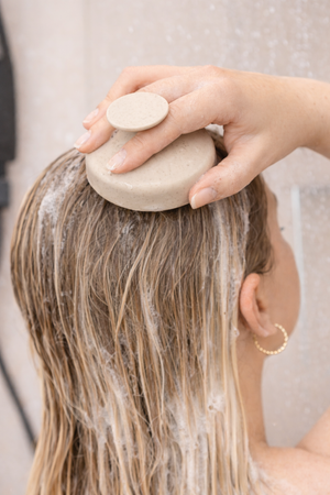 Frau massiert den Daily Glow Up Deep Cleanse Scalp Scrub bei der Haarwäsche in die Kopfhaut ein.