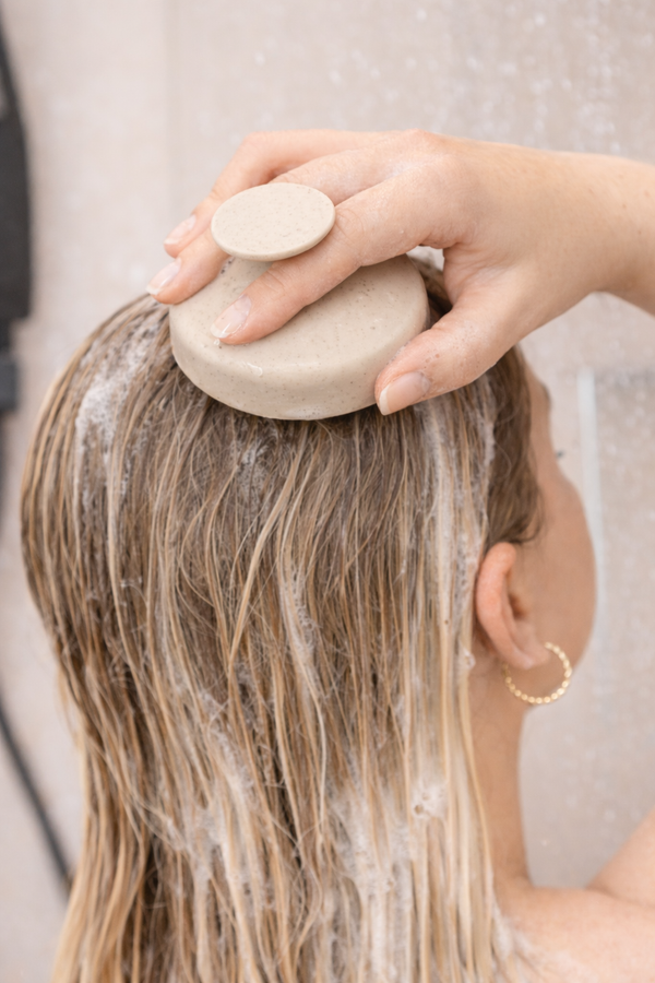 Frau massiert den Daily Glow Up Deep Cleanse Scalp Scrub bei der Haarwäsche in die Kopfhaut ein.
