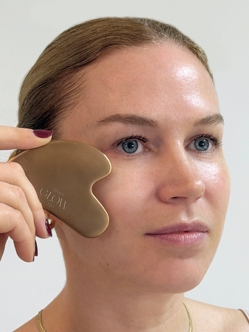 Goldener Gua Sha Stein von Daily Glow Up für eine entspannende Gesichtsmassage.