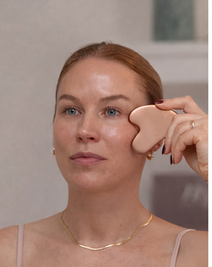 Frau wendet den Daily Glow Up Gua Sha Stein bei einer sanften Gesichtsmassage an.