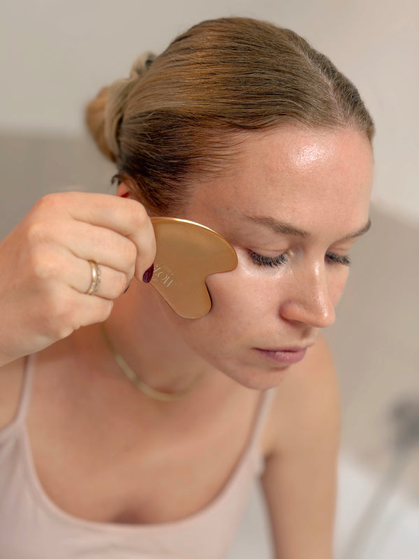 Anwendung des Daily Glow Up Gua Sha Tools mit Facial Oil bei einer Gesichtsmassage.