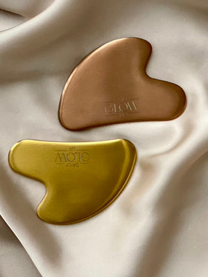 Goldener und bronzefarbener Gua Sha Stein von Daily Glow Up für die Gesichtspflege.