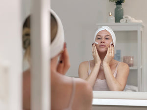 Frau trägt die Daily Glow Up Multi-Hyaluron Tagescreme vor dem Spiegel auf.