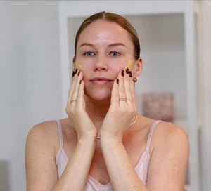 Frau trägt das Daily Glow Up Vitamin C Serum bei der Gesichtspflege auf.
